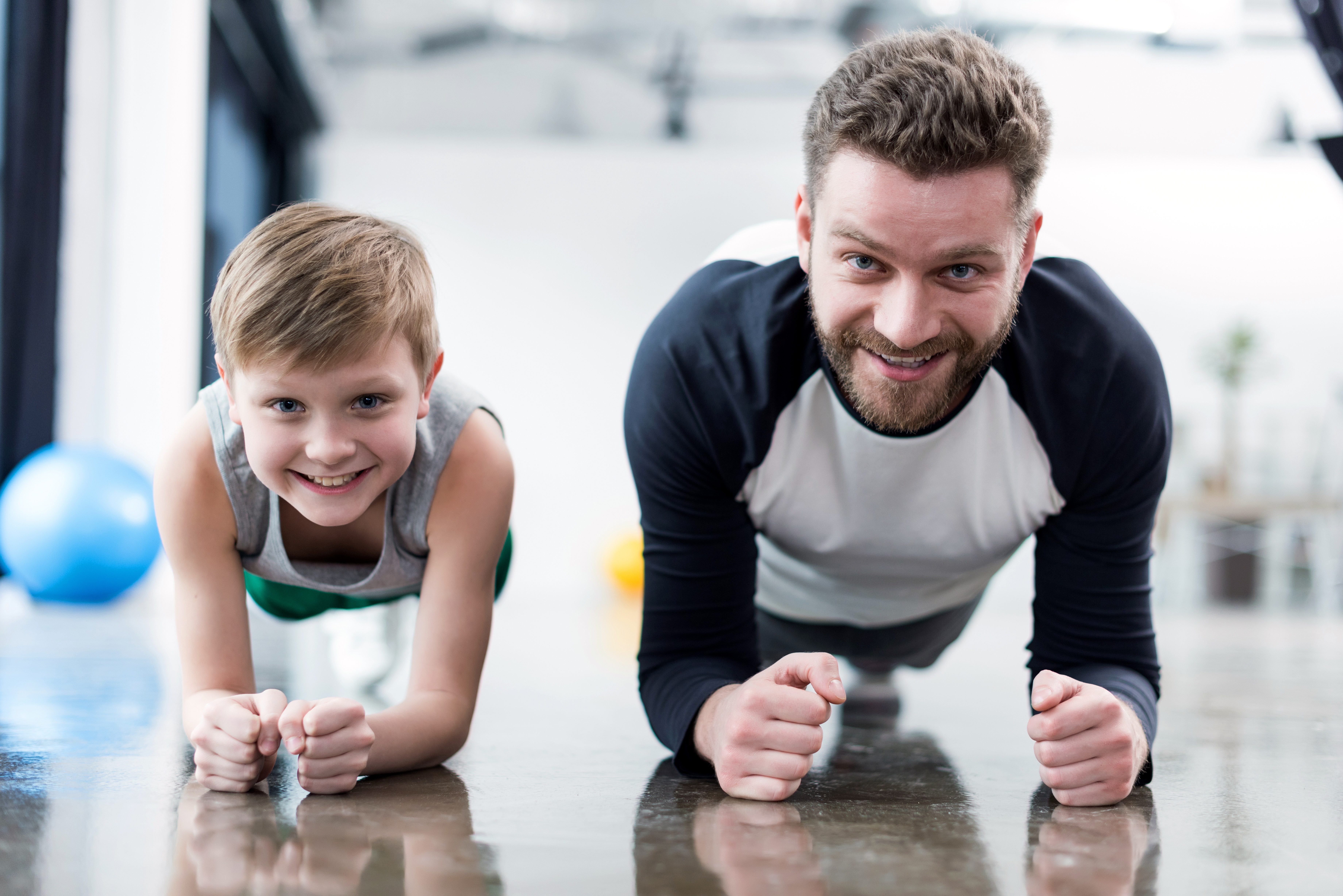 Younger age. Спорт семья. Фитнес семья. Папа и ребенок занимаются спортом. Семья спортсменов.